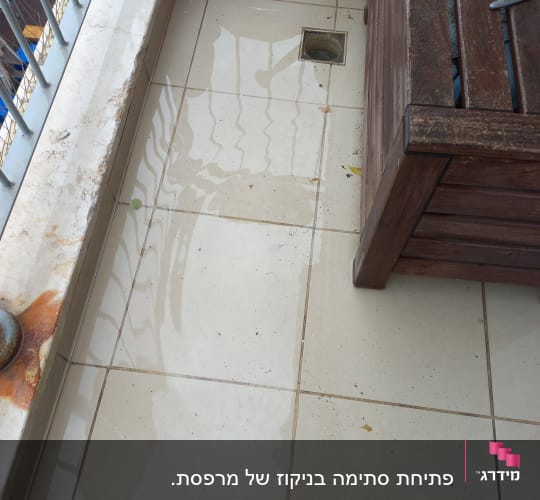 מרפסת עם שלולית מים ליד פתח ניקוז